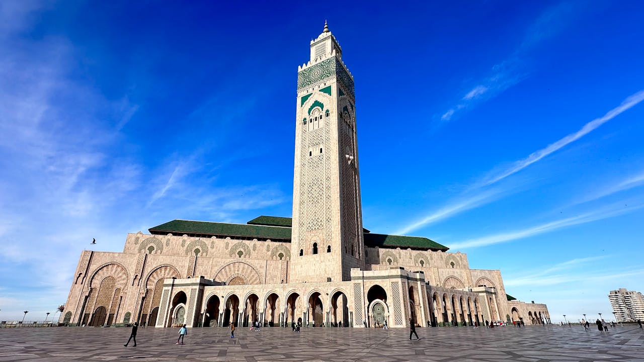 Wide-angle view of the iconic Hassan II Mosque in Casablanca under a clear blue sky.